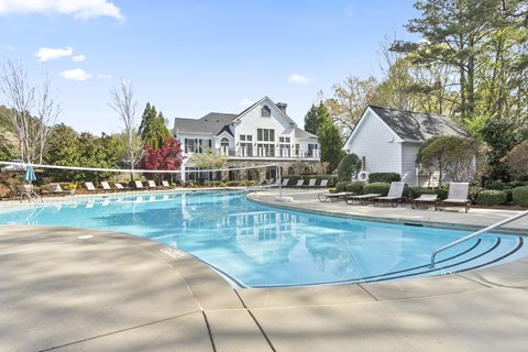 a swimming pool with chaise lounge chairs and a house in the background